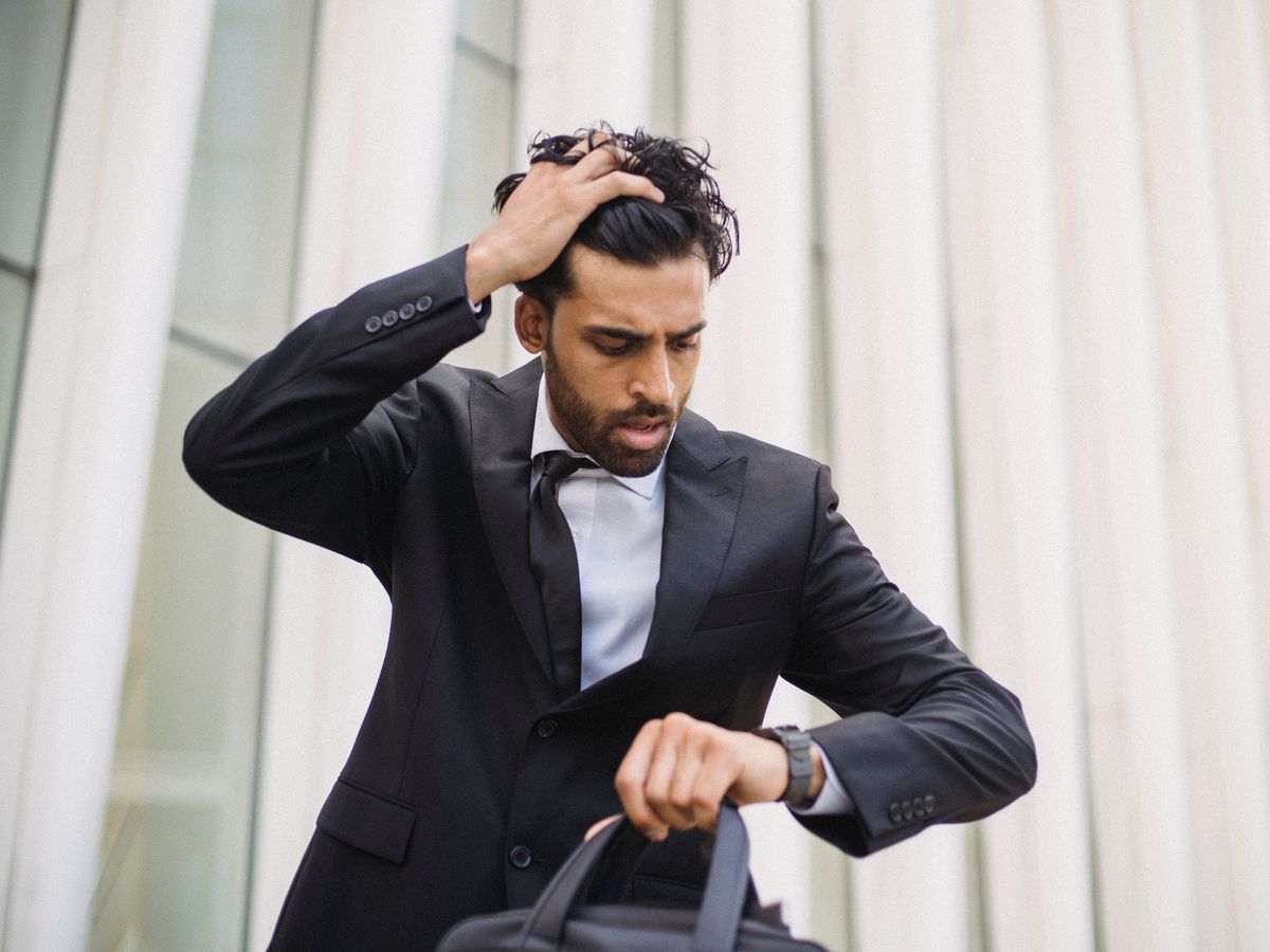 A stressed man in a suit checking his watch, late for work