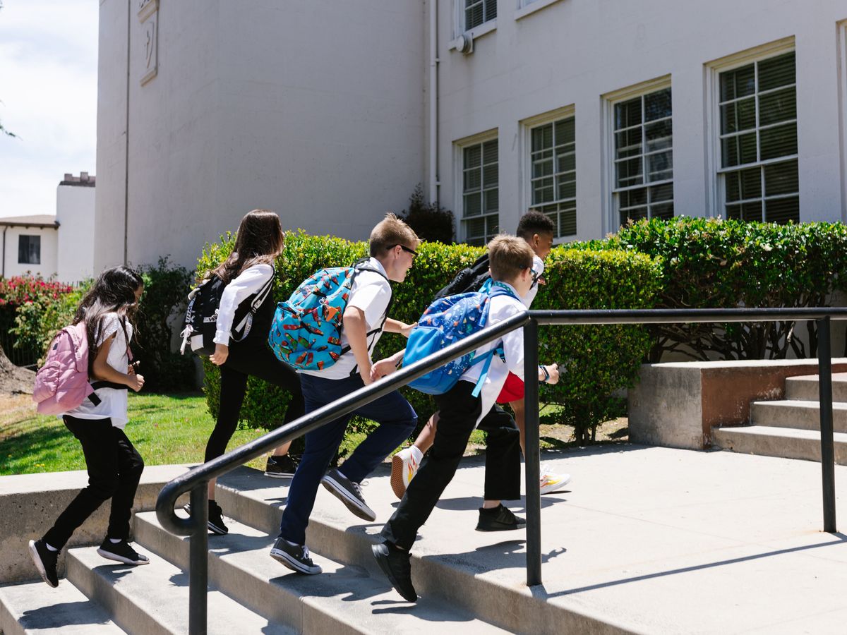 Children with school bags running up the school steps