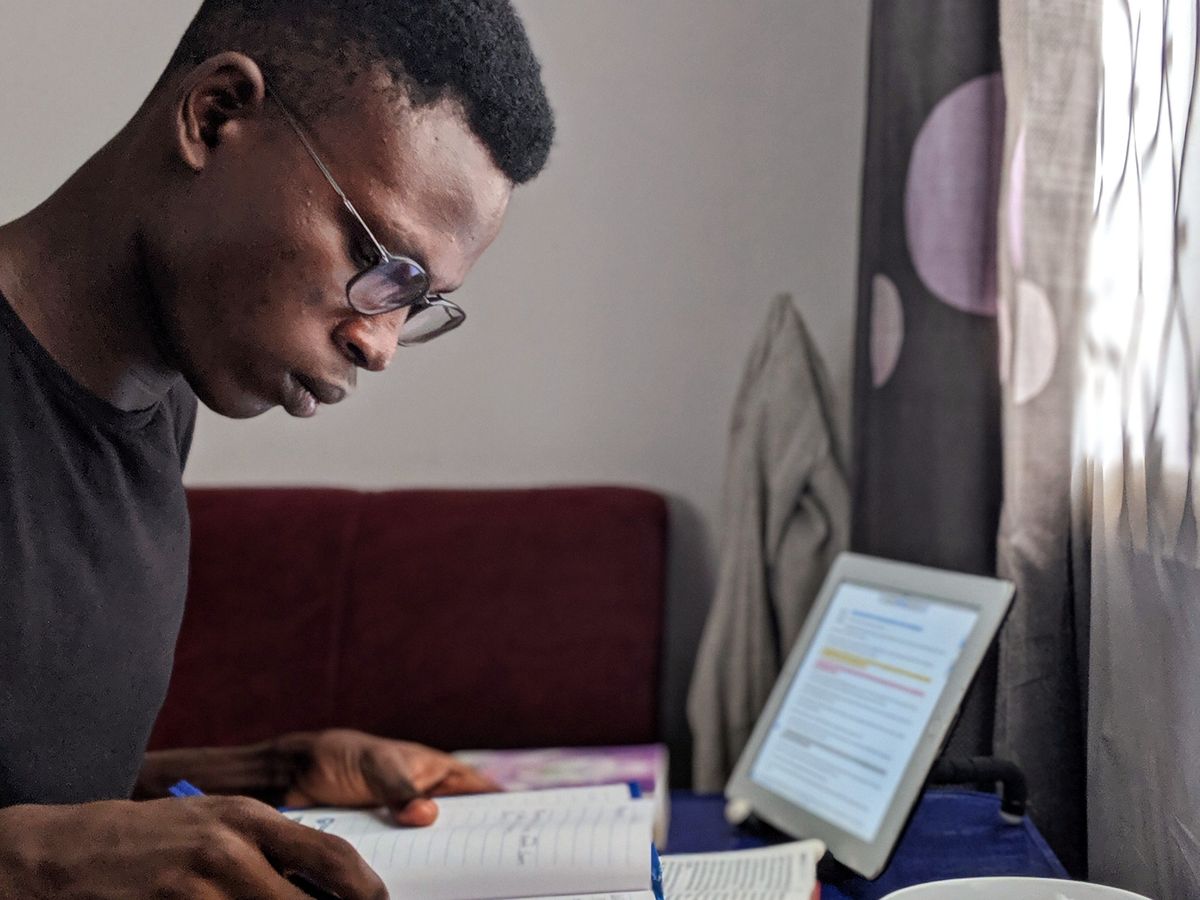 A student studying at a desk with books, a tablet and a coffee cup